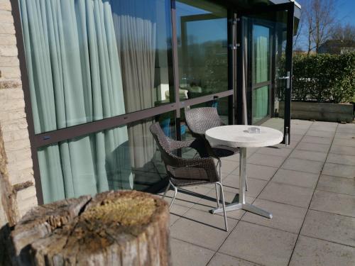 a patio with two chairs and a table on a balcony at Resort Land & Zee in Scharendijke