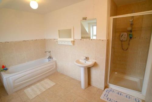 y baño con bañera, lavamanos y ducha. en Atlantic Retreat Portsalon Min 2 ngts, en Portsalon