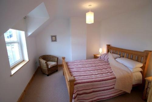 1 dormitorio con 1 cama, 1 silla y 1 ventana en Atlantic Retreat Portsalon Min 2 ngts, en Portsalon