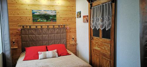 sypialnia z łóżkiem z czerwonymi poduszkami i drewnianą ścianą w obiekcie La grange de Lina w mieście Grignon