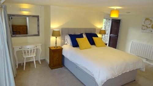 a bedroom with a bed with blue and yellow pillows at The Annex at Middle Filham, Ivybridge in Ivybridge