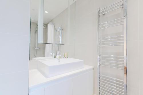 a white bathroom with a sink and a mirror at StayInn Soho Apartments in London