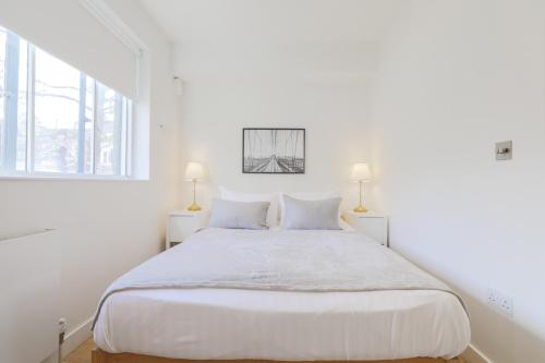 a white bedroom with a large bed and two lamps at StayInn Soho Apartments in London