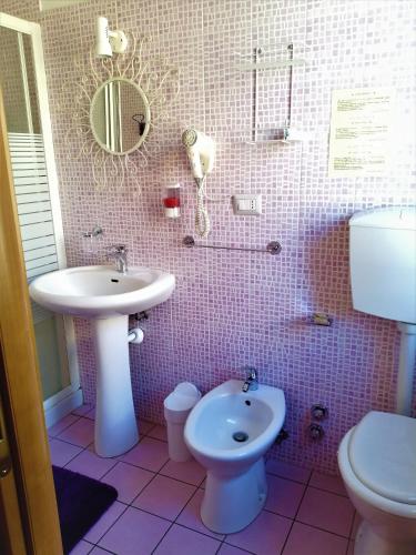 a pink tiled bathroom with a sink and a toilet at Hotel Serenella in Turin