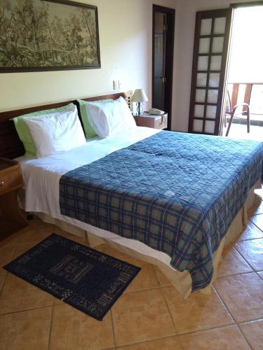 a bedroom with a large bed with a blue blanket at Pousada Muriqui in São Francisco Xavier