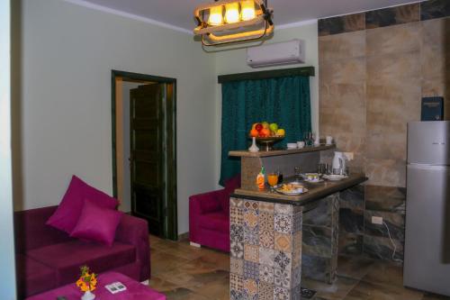 Geo Palace في دهب: غرفة معيشة مع كراسي أرجوانية وثلاجة