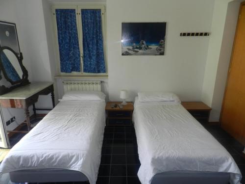 two beds in a room with two windows at Pit Stop in Campagnano di Roma