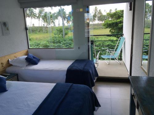 two beds in a room with a view of a balcony at Pousada Brisa e Mar in Praia do Frances