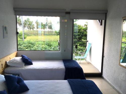 two beds in a room with a large window at Pousada Brisa e Mar in Praia do Frances