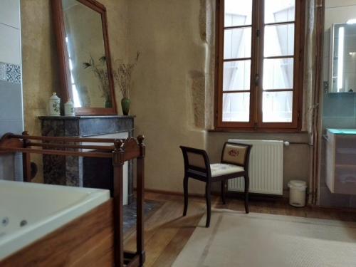 ein Badezimmer mit einem Stuhl, einer Badewanne und einem Spiegel in der Unterkunft Chez Casimir in Cercy-la-Tour