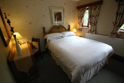 a bedroom with a large white bed and two windows at Three Horseshoes Country Inn in Leek