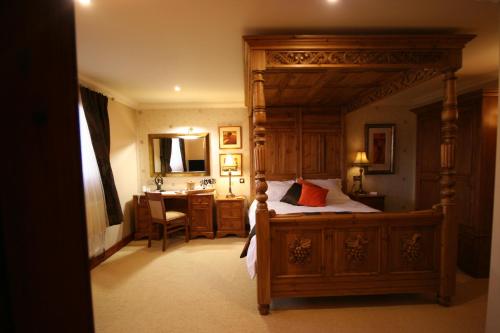 a bedroom with a canopy bed and a desk at Three Horseshoes Country Inn in Leek