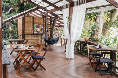 an outdoor patio with tables and chairs and a swing at Bonito Paraiso Ilha Grande in Abraão