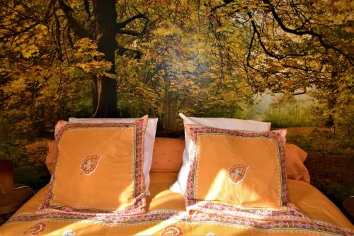 a bed with two pillows on it with a painting at B&B Au fil des saisons sur la Wiels in Fauvillers