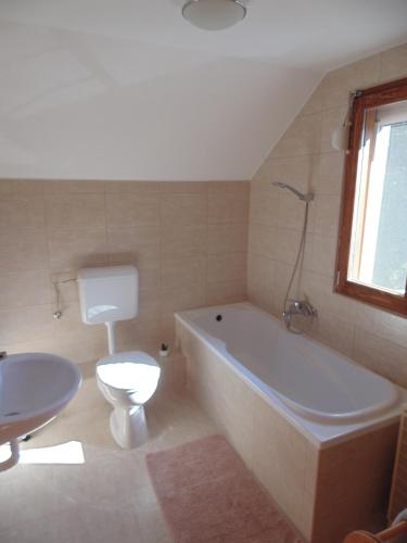 a bathroom with a tub and a toilet and a sink at Azúr Vendégház in Hajdúszoboszló