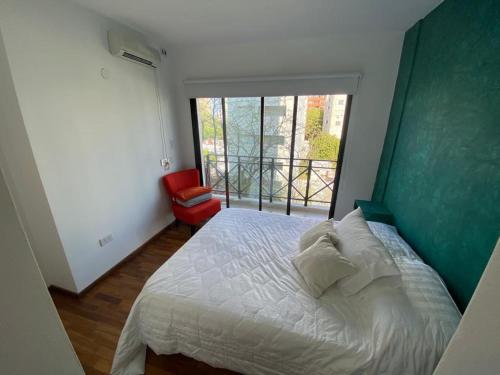 a bedroom with a bed with a green headboard and a window at Vittorio 55 in La Plata