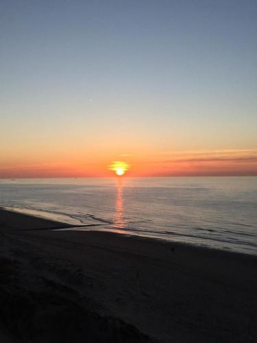 a sunset on the beach with the sun setting at Studio On The Beach With Sea View in Middelkerke
