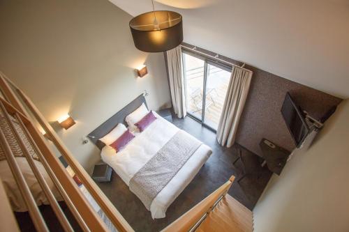 um pequeno quarto com uma cama e uma janela em LOGIS Hôtel-restaurant IMAGO em La Roche-Clermault
