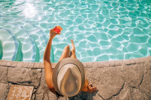 a woman in a hat laying next to a swimming pool at Casa De Rosa Apartments & Studios in Svoronata