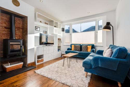 a living room with a blue couch and a fireplace at Charming 3 Bedroom House garden & parking - next to CS Lewis Nature Reserve in Oxford
