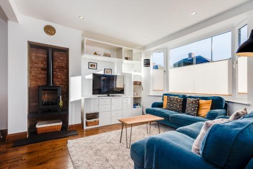 a living room with a blue couch and a tv at Charming 3 Bedroom House garden & parking - next to CS Lewis Nature Reserve in Oxford
