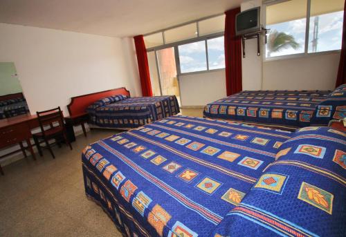 a hotel room with three beds and a table and chairs at Hotel Royalty in Veracruz