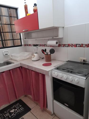 a kitchen with red and white cabinets and a stove at Maria Jose Bungalows in Zorritos