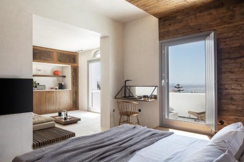 a bedroom with a bed and a large window at TinosVillages in Tinos