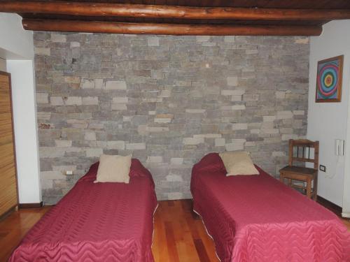 duas camas num quarto com uma parede de tijolos em Jardín de Iris em Maipú