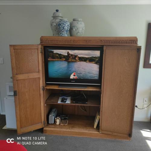 a television in a wooden entertainment center at Castor Bay Homestay in Auckland