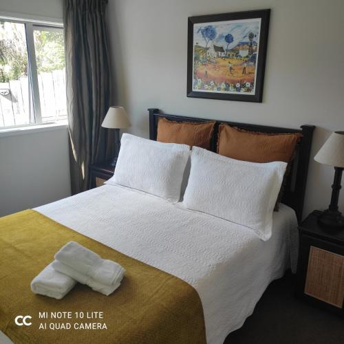 a bedroom with a large bed with white sheets and pillows at Castor Bay Homestay in Auckland