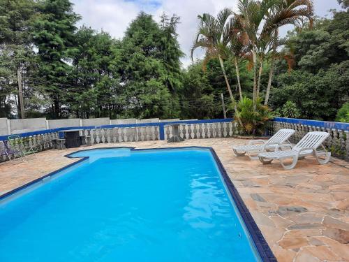 una piscina con 2 tumbonas junto a una valla en Hospedagem Chalé pousada Chácara Cantinho do Mozão en São Roque