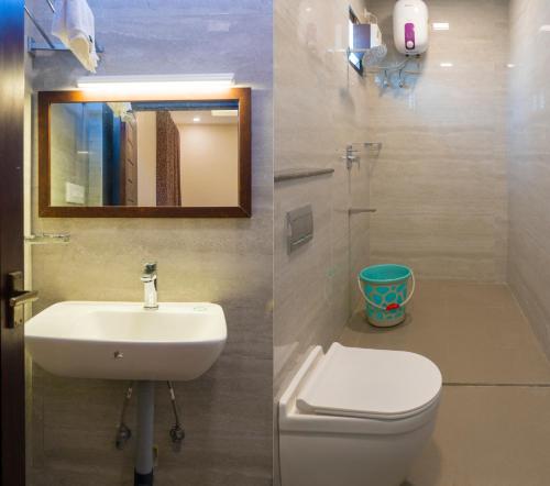 a bathroom with a toilet and a sink and a mirror at Pranaav Beach Resort in Puducherry