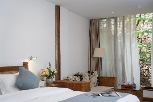 a bedroom with a bed and a chair and a window at Lijiang Merry Inn in Lijiang