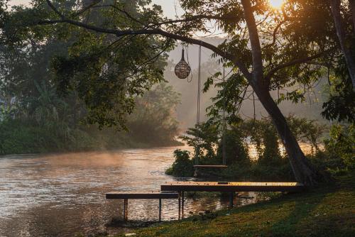 a picnic table and bench next to a river at The Tree Riverside Kaeng Krachan in Kaeng Krachan