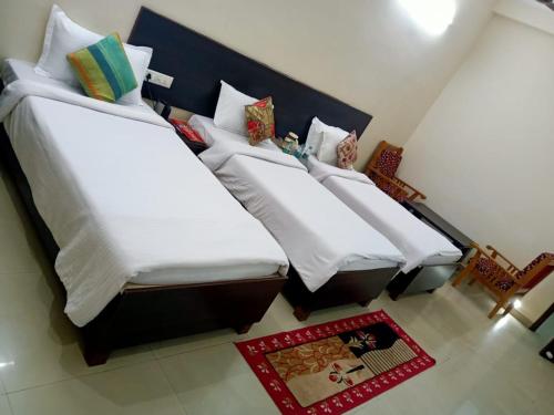 three beds in a room with white sheets and pillows at Hotel the Ideal in Kushinagar