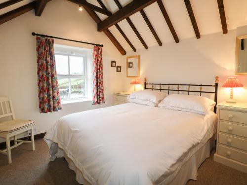 a bedroom with a large white bed and a window at Walton Cottage in Winster