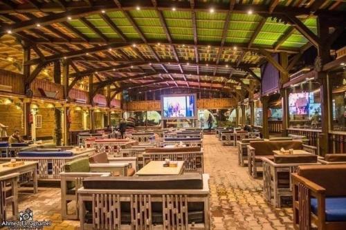 قرية النورس السياحية في بورسعيد: غرفة طعام مع طاولات وشاشة كبيرة