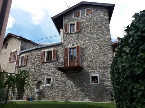 a large stone building with windows and a balcony at Independent Stone House with Lake View in Musso