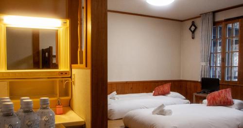 a hotel room with two beds and a mirror at Kizuna Lodge & BBQ Centre in Hakuba