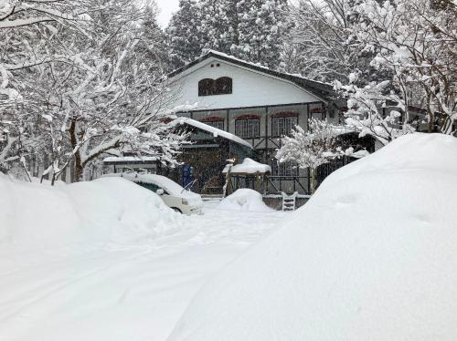 a pile of snow in front of a house at Kizuna Lodge & BBQ Centre in Hakuba