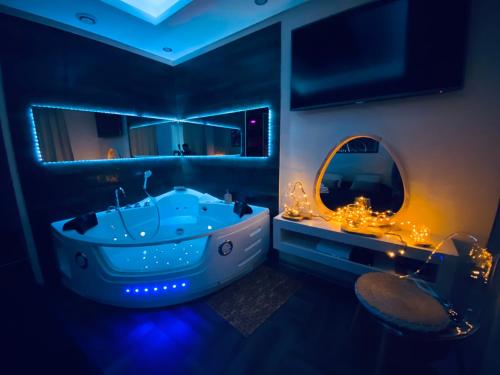 a bathroom with a blue tub and a mirror at Le Rêve d'une Nuit suite Amour in Sarreguemines