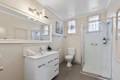 a white bathroom with a shower and a toilet at Spacious 4 Bdrms near Murray River, Pet Friendly in Strathmerton