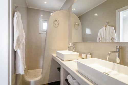 a white bathroom with a sink and a mirror at Amoramelia Villas in Imerovigli