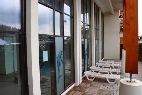 une rangée de chaises blanches sur un balcon avec fenêtres dans l'établissement Residence VAL DAZUR VALBERG 2 PIECES, à Valberg
