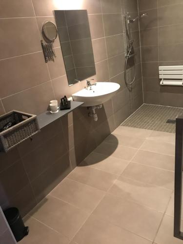 a bathroom with a sink and a shower at Hôtel Le Sens in Vaux-sur-Mer