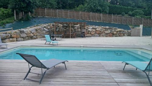 a swimming pool with two chairs and a table at LOU CHASTEL, DEMEURE PERIGOURDINE CLIMATISEE avec PISCINE PRIVEE et CHAUFFEE in La Bachellerie