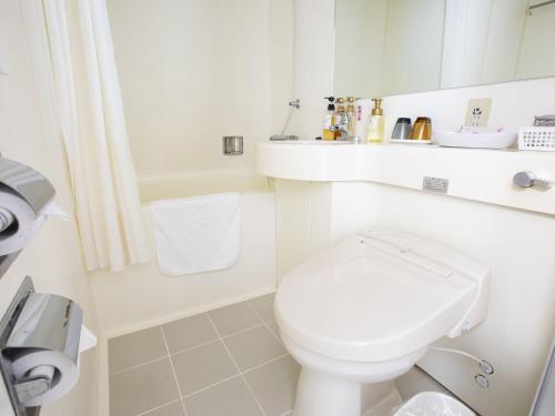 La salle de bains blanche est pourvue de toilettes et d'un lavabo. dans l'établissement Hotel Wing International Hitachi, à Hitachi