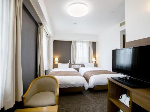 a hotel room with two beds and a flat screen tv at KOKO STAY Hitachi- formerly Hotel Wing International Hitachi in Hitachi