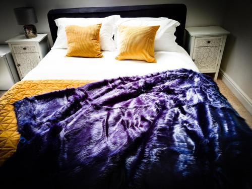a bed with a purple blanket and two pillows at White Horse Inn in Chester